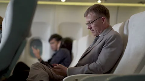 Businessman passengers using smartphone sitting in airplane Stock Footage 167056751