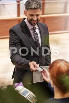 Businessman paying clerk with credit cart at menswear shop Stock Photos