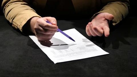 A businessman with a pen is considering a document. Stock Footage 129786658