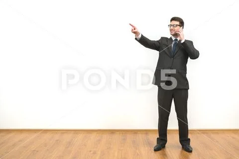 The businessman phones and gestures on the white wall background Stock Photos