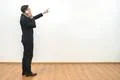 The businessman phones and gestures on the white wall background Photo