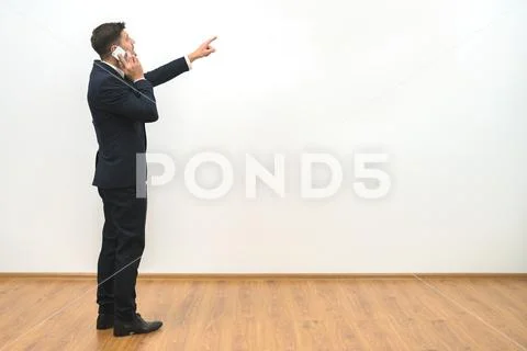 The businessman phones and gestures on the white wall background Stock Photos