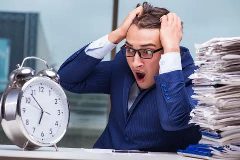 Businessman with pile stack of paper paperwork and an alarm cloc Foto stock
