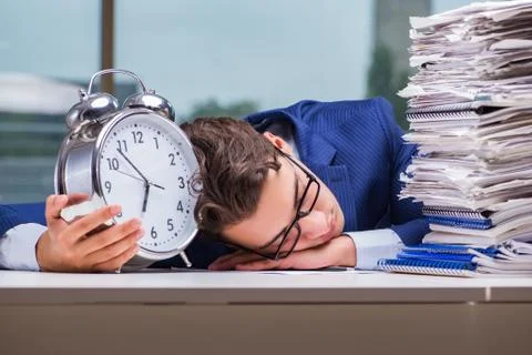 Businessman with pile stack of paper paperwork and an alarm cloc Foto stock
