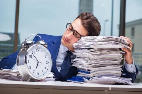 Businessman with pile stack of paper paperwork and an alarm cloc Foto stock