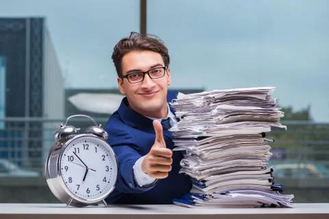 Businessman with pile stack of paper paperwork and an alarm cloc Foto stock