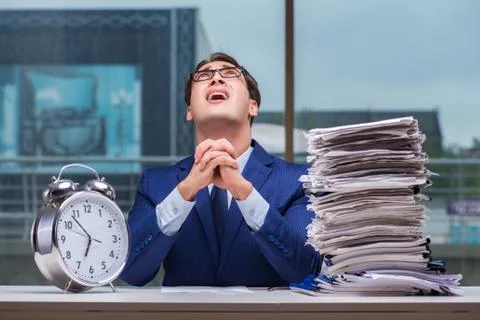 Businessman with pile stack of paper paperwork and an alarm cloc Foto stock