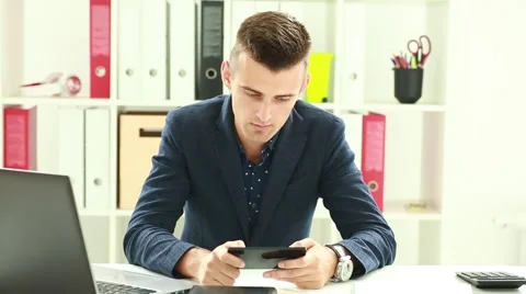 Businessman Playing games in the office using a smartphone and wins Stock Footage