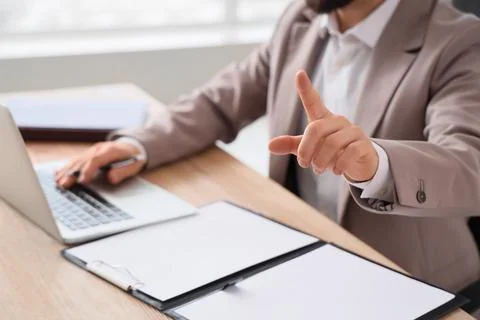 Businessman pointing finger while working on laptop at a wooden desk in a mod Stockfoto's