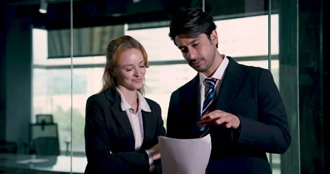 Businessman pointing at report while discussing with businesswoman in office Stock Footage 328566507