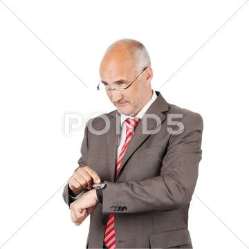 Businessman pointing at wristwatch while looking away Stock Photos