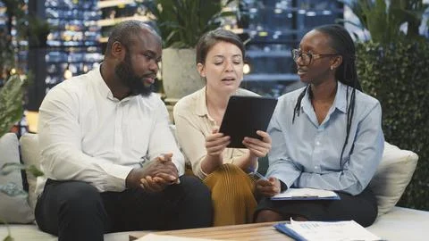 Businessman points to tablet screen during rooftop lounge workspace presentation Stock Photos