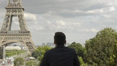 Businessman posing at the Eiffel Tower after work, with a black jacket, brown 動画素材 111923753