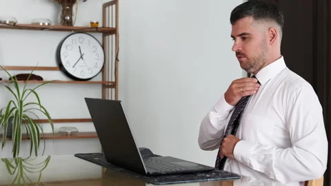 Businessman prepares for virtual call by fixing his tie. Stock Footage 310681059