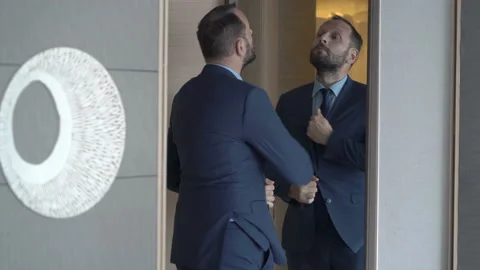 Businessman preparing himself in front of the mirror and goes out Stock Footage 97724140