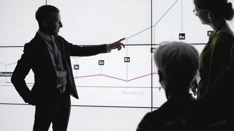 Businessman presenting data to colleagues on a digital wall Stock Footage 138983387