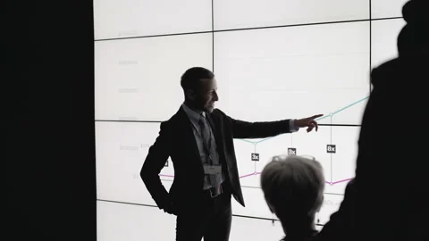 Businessman presenting data on a digital wall in a dark office Stock Footage 138983621