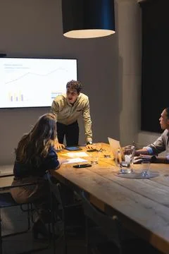 Businessman presenting data on screen during late-night meeting in modern office Stock Photos