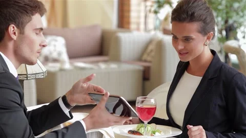 Businessman presenting data on a tablet during a lunch meeting Stock Footage 311182122