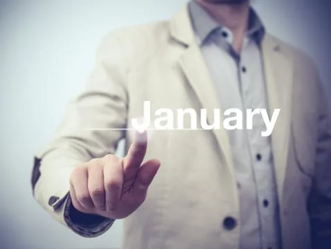 Businessman pressing button on virtual screen January button - concept Stock Photos
