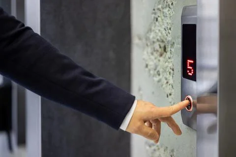 Businessman pressing an elevator button in modern building Stockfoto's