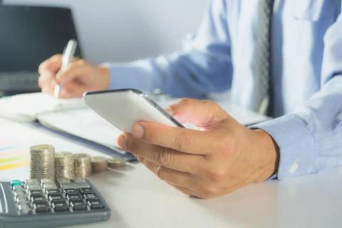 Businessman process with writing and using smart phone. Businessman working t Stock Photos