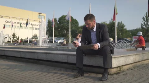Businessman pulls out smartphone, browsing tablet. Stock Footage 52755244