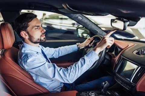Businessman pushing button on the rear view mirror in car Stock Photos