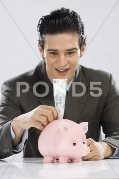 Businessman putting one hundred rupees note in a piggy bank Stock Photos