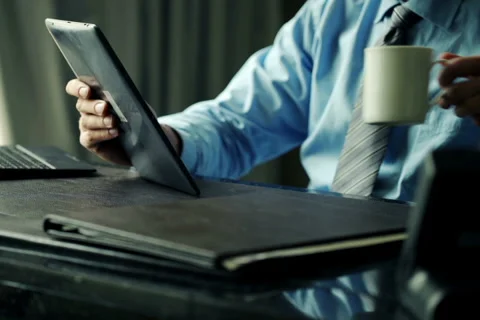 Businessman reading something on tablet computer by desk at office NTSC Stock Footage 54680689