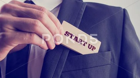 Businessman removing a wooden card reading Start up from his pocket Stock Photos