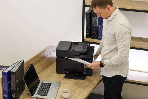 Businessman retrieving printed document from printer Stock Photos