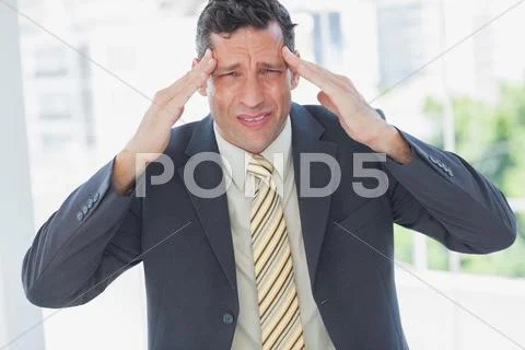 Businessman rubbing his temples and frowning at camera Stock Photos