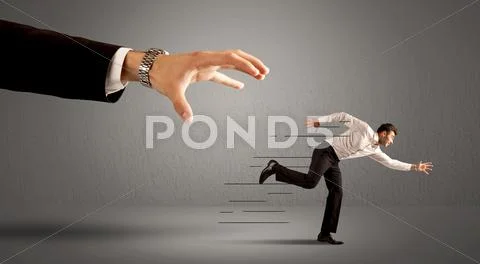 Businessman running away from a huge hand Stock Photos