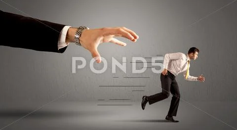 Businessman running away from a huge hand Stock Photos