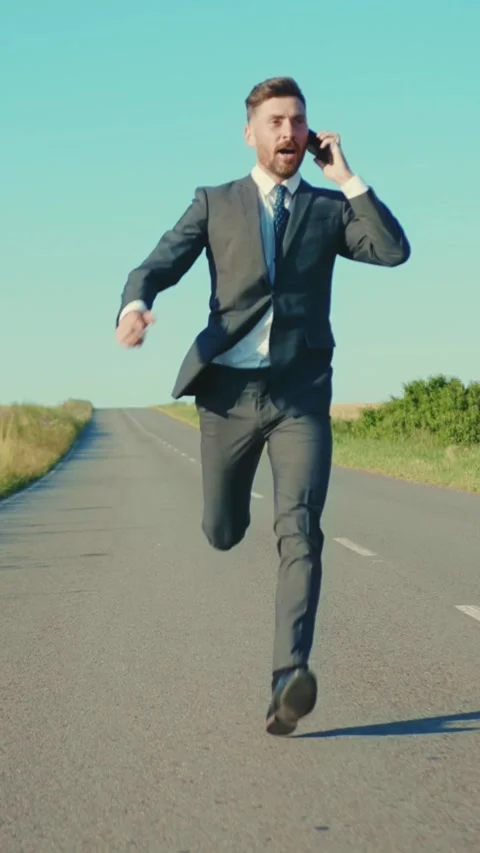 A Businessman Running Solemnly on an Empty Road While Dressed Smartly in a Suit Stock Footage 314367676