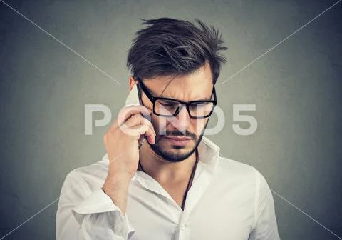 Businessman with sad expression talking on mobile phone looking down Stock Photos