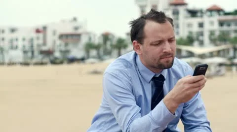 Businessman sending text message on cellphone and smiling, outdoors HD Stock Footage