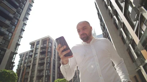 A businessman with a serious expression is walking and texting on the phone. Stock Footage 204848890