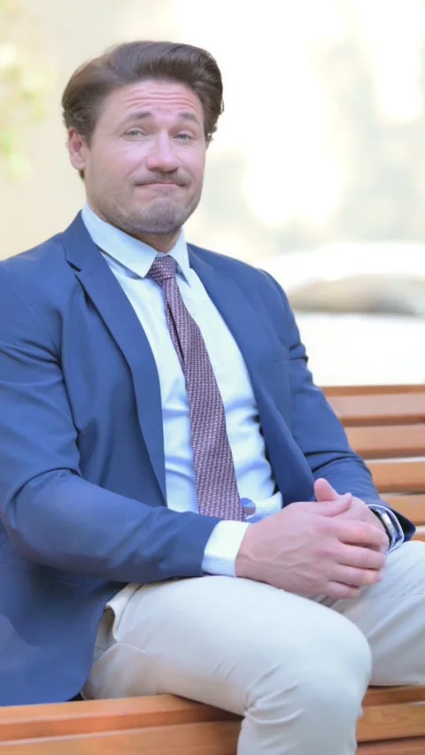 Businessman Shaking Head in Acceptance while Sitting Outdoor, vertical Stock Footage 321119542