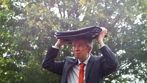 Businessman sheltering underneath his bag in the rain Stock Footage 80925558