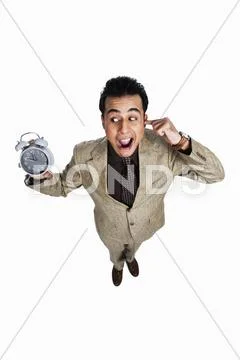 Businessman showing an alarm clock and looking irritated Stock Photos