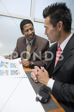 Businessman Showing Blueprints To His Business Partner Stock Photos
