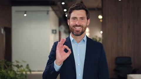 Businessman showing ok gesture while expressing positive emotion at office 스톡 동영상 251802913
