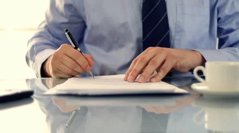 Businessman signing documents on reflective table and drinking coffee Stock Footage 2203866