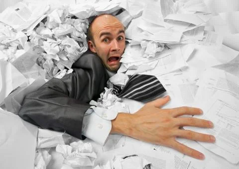 Businessman sinking in heap of documents Stock Photos