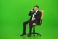 The businessman sit of the chair and call on the green background Photo