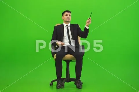 The businessman sit of the chair and gesture on the green background Stock Photos