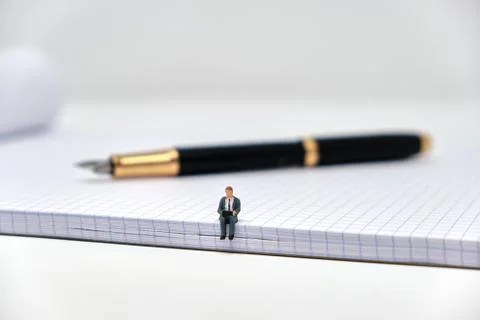 A businessman sits on  a squared notepad working with a pen in the background Stock Photos