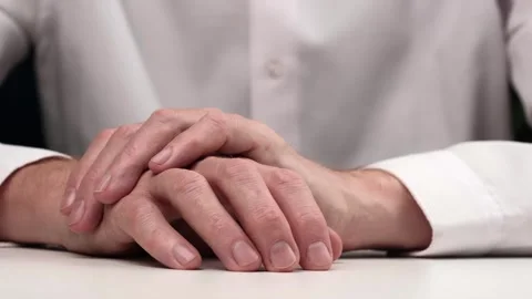 Businessman sits at table put one hand on other and taps his fingers in thought. Stock Footage 256793251